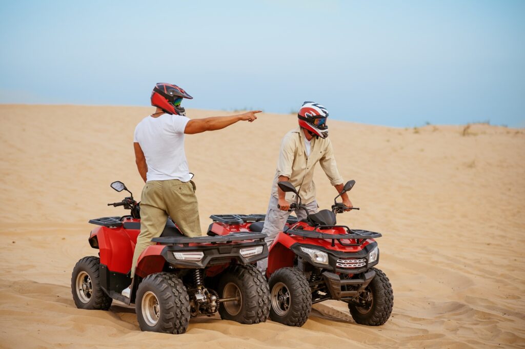 Two riders in helmets on an ATV quad bike in the Hurghada desert